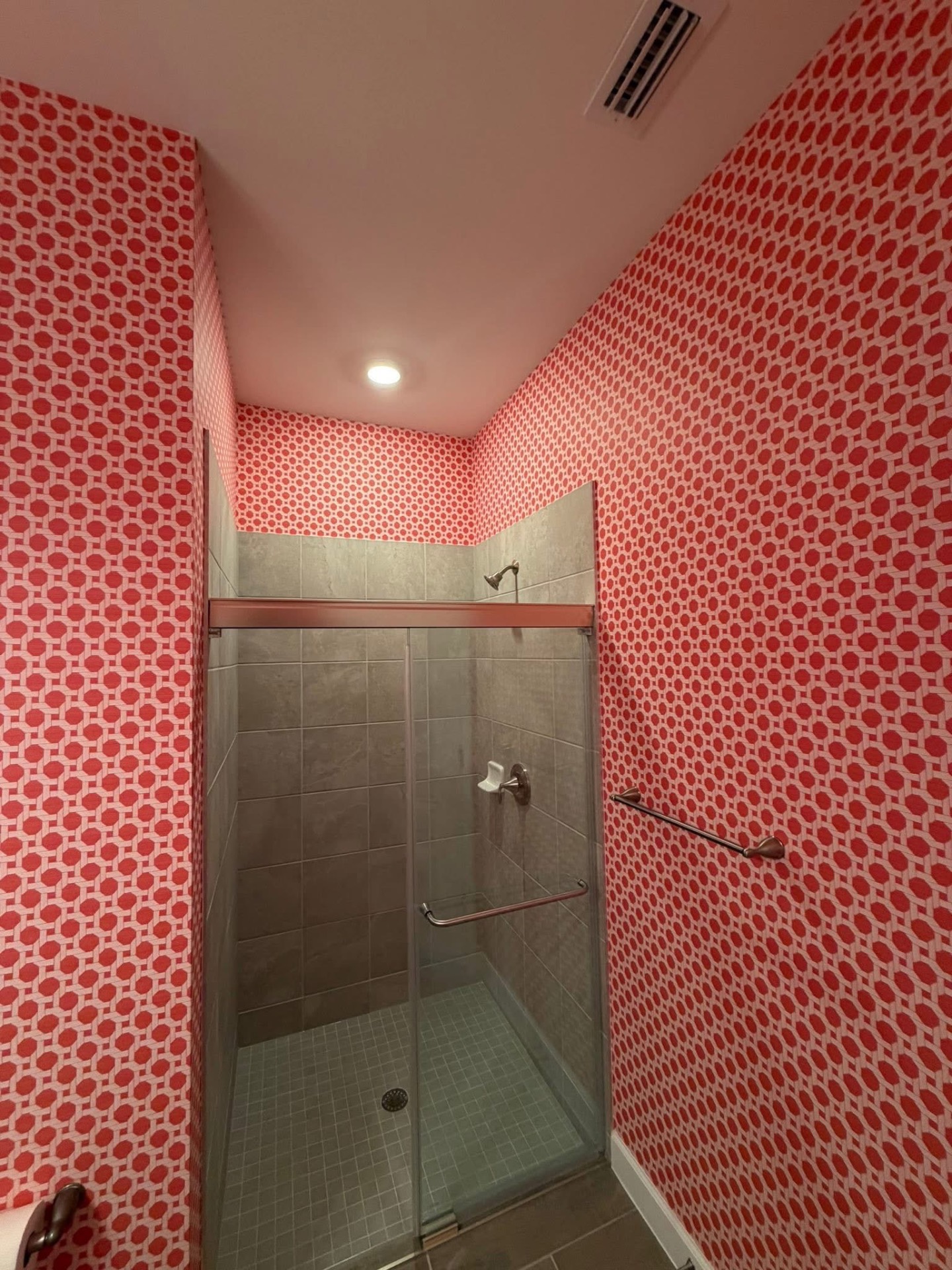 Coral red honeycomb wallpaper surrounding a spa shower
