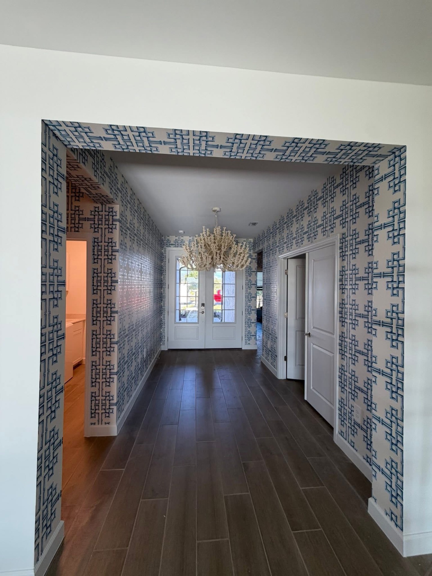Blue Chinese fretwork wallpaper wrapping a grand entry hallway